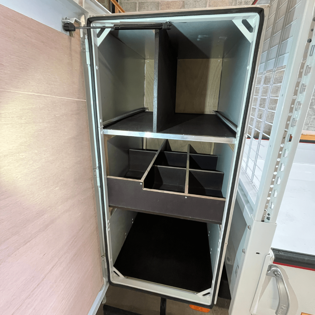 Côté gauche du coffre d’un camion benne Iveco Daily, aménagé avec des étagères et des compartiments pour un rangement ordonné et pratique du matériel.