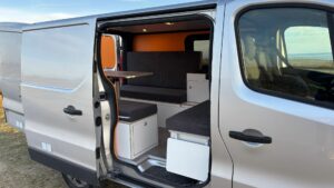 Fiat Talento II 2021 aménagé avec banquettes, table modulable et cuisine intégrée, parfait pour les voyages en van.