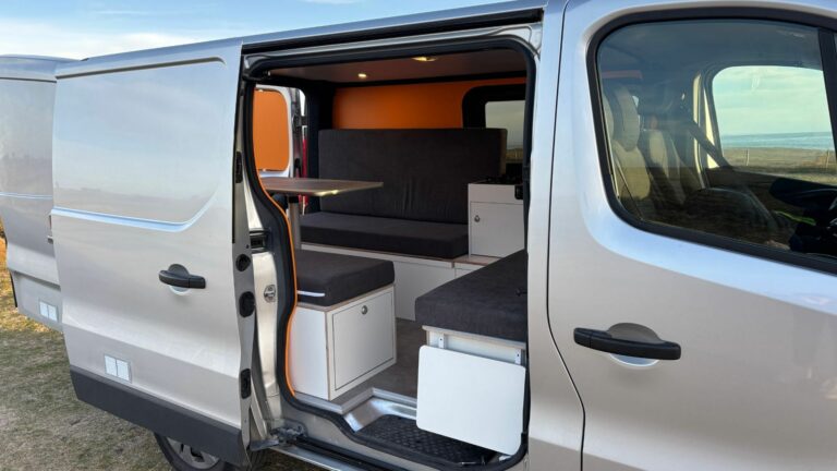 Fiat Talento II 2021 aménagé avec banquettes, table modulable et cuisine intégrée, parfait pour les voyages en van.