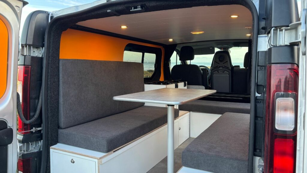 Fiat Talento II 2021 aménagé avec coin repas, banquettes confortables et rangements intégrés pour les voyages en van.