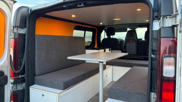 Fiat Talento II 2021 aménagé avec coin repas, banquettes confortables et rangements intégrés pour les voyages en van.