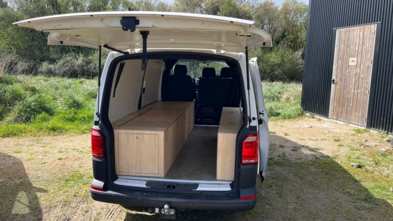 Volkswagen T6 aménagé avec deux meubles de rangement en bois sur mesure optimisant l’espace arrière du véhicule.