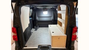 Aménagement Peugeot Expert cabine approfondie avec meuble de rangement en bois sur mesure et étagères latérales intégrées.