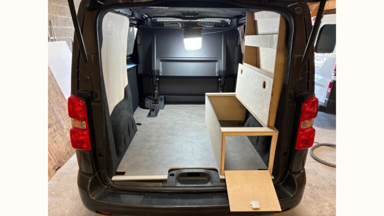 Aménagement Peugeot Expert cabine approfondie avec meuble de rangement en bois ouvert et trappe frontale pour accès rapide au matériel.